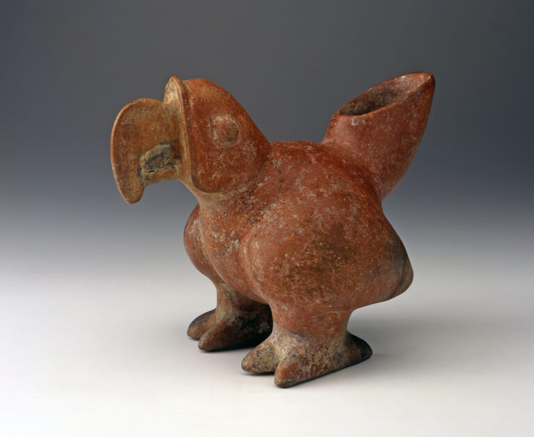 A reddish-brown ceramic vessel shaped like a parrot with the tail as the spout.