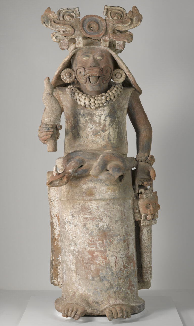 Ceramic sculpture of a female holding a torch in her right hand and a bag in her left hand.