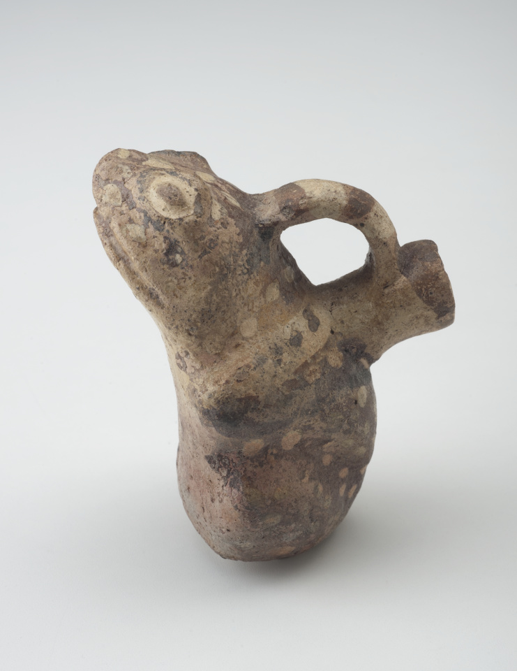 A ceramic vessel shaped like a frog, with a handle connecting the top of the frog’s head to a spout on its back.