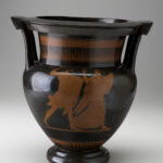 Shiny black ceramic vessel with two handles shows a painted reddish-brown design of a bearded man chasing a woman with a three-pronged spear.