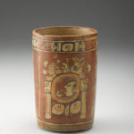 A red cylindrical ceramic vase decorated with designs and motifs in cream, black, and orange.